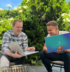 Kobeon teamleden lachen buiten met laptop